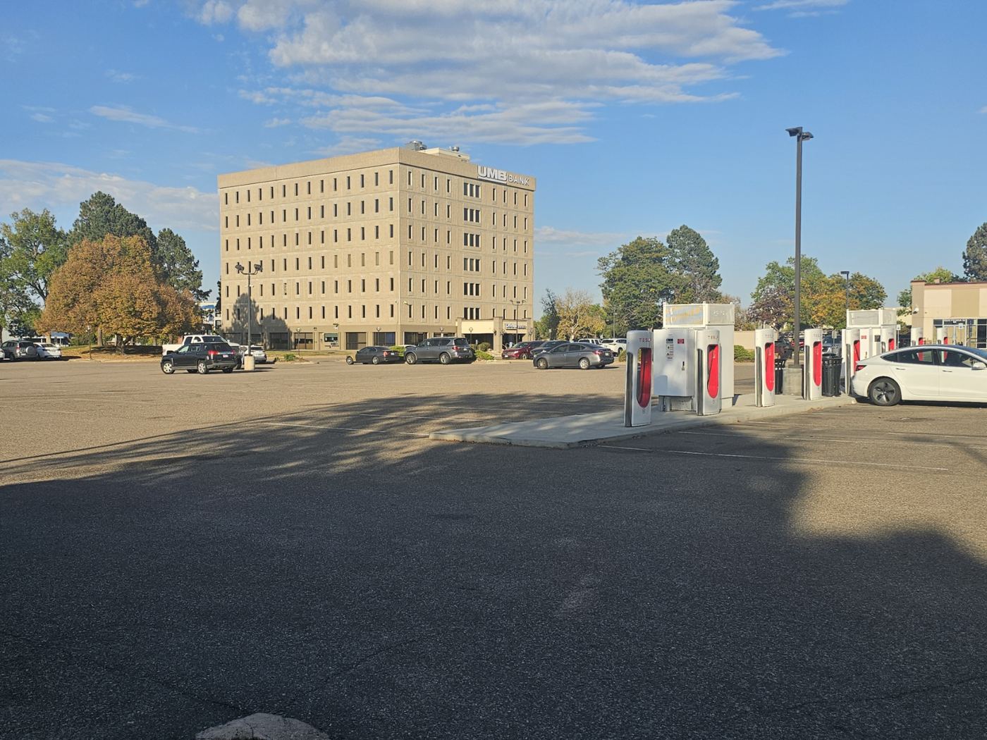 Surface parking lot with Tesla charging stalls, the building behind